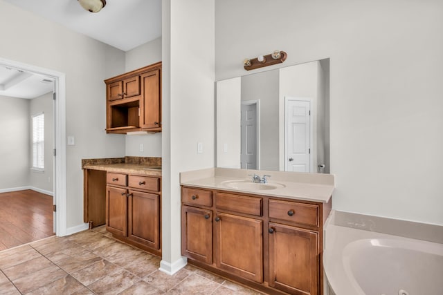 bathroom featuring baseboards, a tub with jets, and vanity