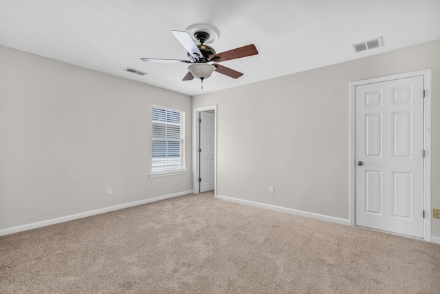 unfurnished room featuring light carpet, a ceiling fan, visible vents, and baseboards