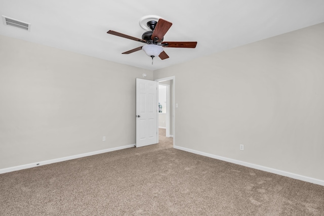 empty room with carpet, visible vents, a ceiling fan, and baseboards