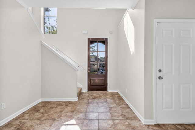 foyer entrance with baseboards and stairway