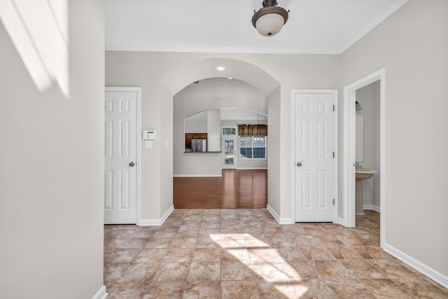 interior space with ornamental molding, baseboards, and arched walkways