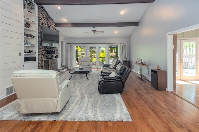 living area with a wealth of natural light, wood finished floors, a ceiling fan, and lofted ceiling with beams