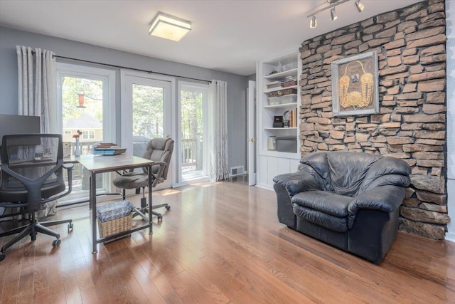 office area featuring visible vents, built in shelves, hardwood / wood-style flooring, and a healthy amount of sunlight