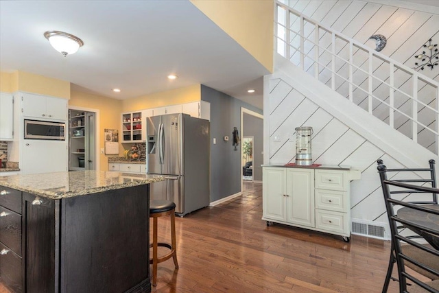 kitchen with light stone counters, dark wood-style floors, visible vents, and stainless steel appliances