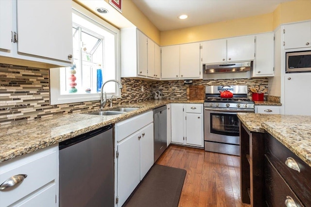 kitchen with stainless steel appliances, under cabinet range hood, a sink, and backsplash