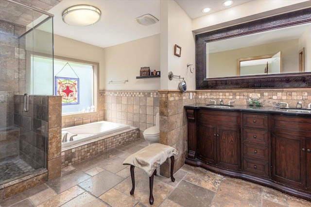 bathroom with a shower stall, stone tile floors, and tile walls