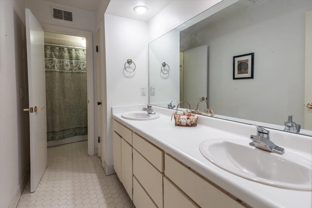 bathroom with a sink, visible vents, double vanity, and tile patterned flooring