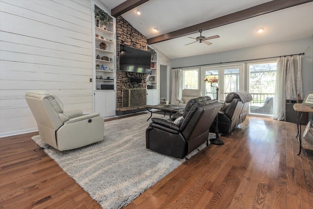living room featuring wood finished floors, ceiling fan, lofted ceiling with beams, and a stone fireplace
