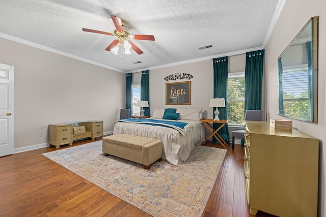 bedroom featuring visible vents, a textured ceiling, ornamental molding, and wood finished floors