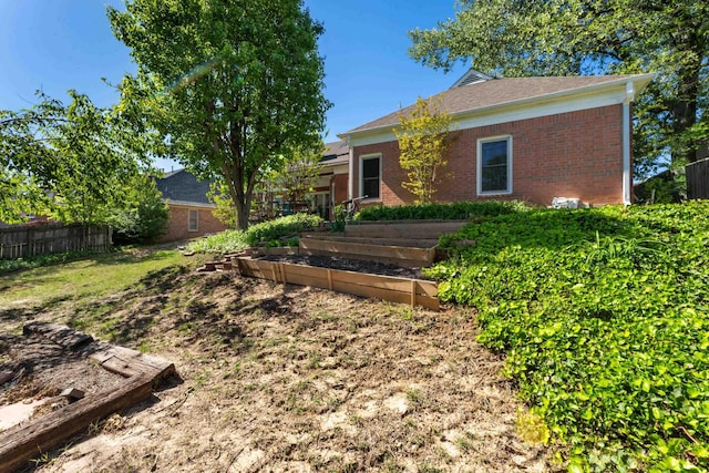 view of front facade with fence, a vegetable garden, and brick siding