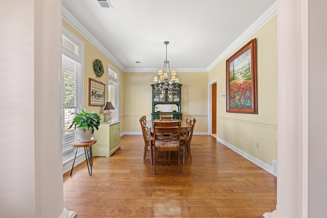 dining room with visible vents, baseboards, a chandelier, crown molding, and light wood finished floors