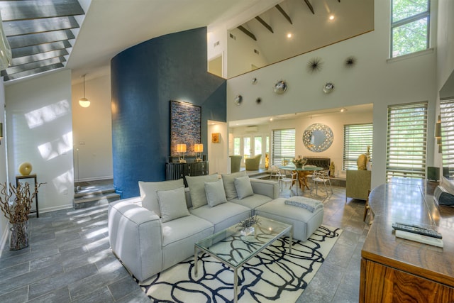 living area with beam ceiling, baseboards, and high vaulted ceiling