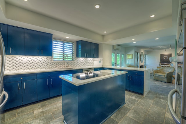kitchen with a sink, blue cabinets, open floor plan, black electric cooktop, and a peninsula