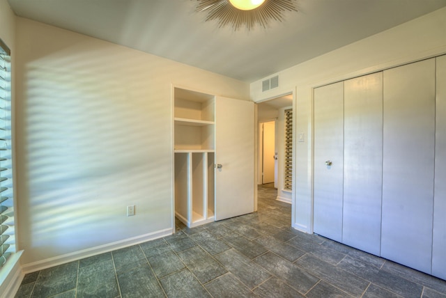 unfurnished bedroom with a closet, visible vents, and baseboards