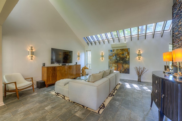 living area with a healthy amount of sunlight, a towering ceiling, and a wall unit AC
