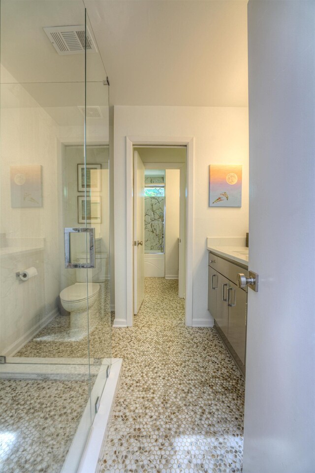 bathroom with toilet, a stall shower, baseboards, visible vents, and vanity