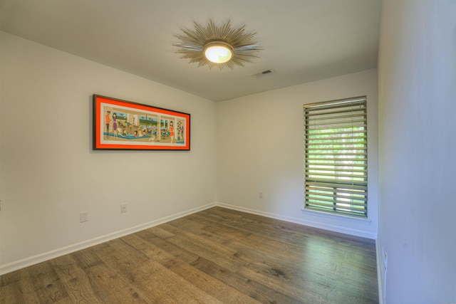 spare room featuring wood finished floors, visible vents, and baseboards
