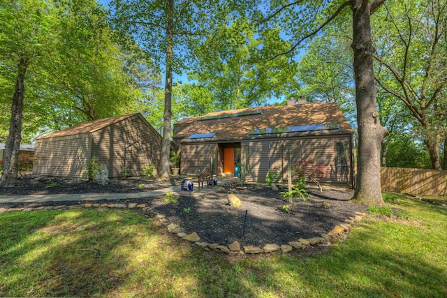 rear view of property with an outbuilding, a chimney, fence, and a lawn