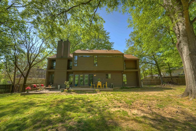 back of property featuring a yard, a patio, a fenced backyard, and a chimney