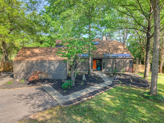 view of front of property featuring fence, a chimney, roof with shingles, and a front yard