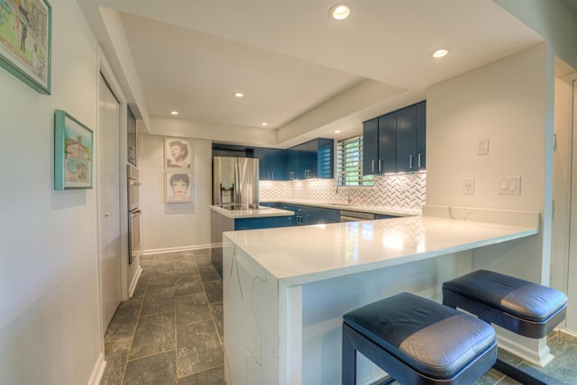 kitchen featuring stainless steel appliances, a peninsula, blue cabinetry, and tasteful backsplash