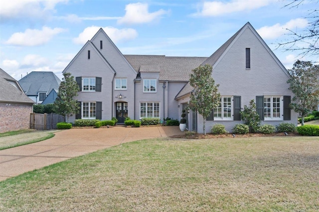 703 Justana Dr, Collierville, TN 38017 - french country style house featuring driveway, an attached garage, fence, a front yard, and brick siding