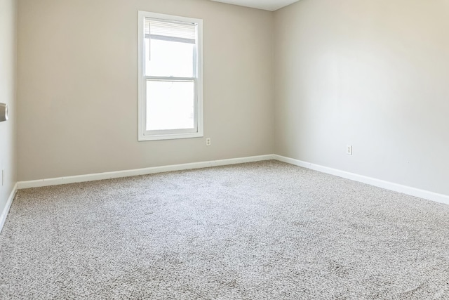 carpeted empty room featuring baseboards
