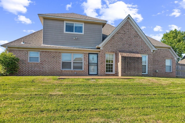rear view of property with brick siding, a yard, and roof with shingles
