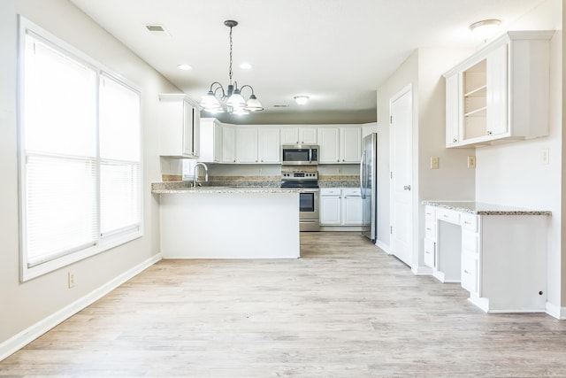 kitchen featuring a sink, light wood-style floors, a peninsula, appliances with stainless steel finishes, and a notable chandelier