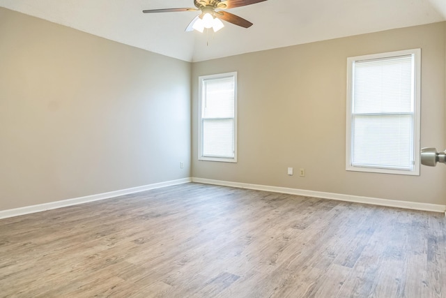 empty room with lofted ceiling, wood finished floors, a ceiling fan, and baseboards