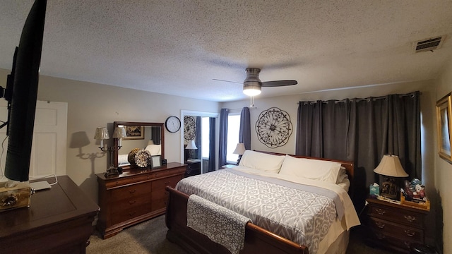 bedroom featuring dark colored carpet, visible vents, a textured ceiling, and a ceiling fan