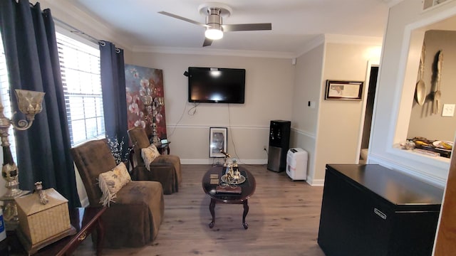 living area with wood finished floors, visible vents, ornamental molding, baseboards, and ceiling fan