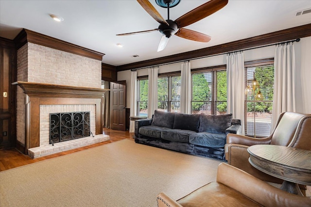 living room with a fireplace, a ceiling fan, wood finished floors, and plenty of natural light