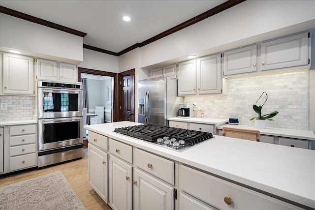 kitchen with light countertops, a warming drawer, crown molding, tasteful backsplash, and appliances with stainless steel finishes