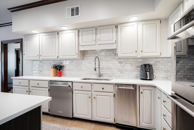 kitchen featuring tasteful backsplash, a sink, light countertops, white cabinets, and visible vents