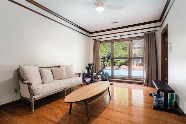 living room featuring light wood-style flooring, visible vents, a ceiling fan, and ornamental molding