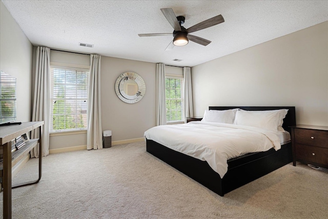 bedroom featuring a textured ceiling, light colored carpet, and visible vents