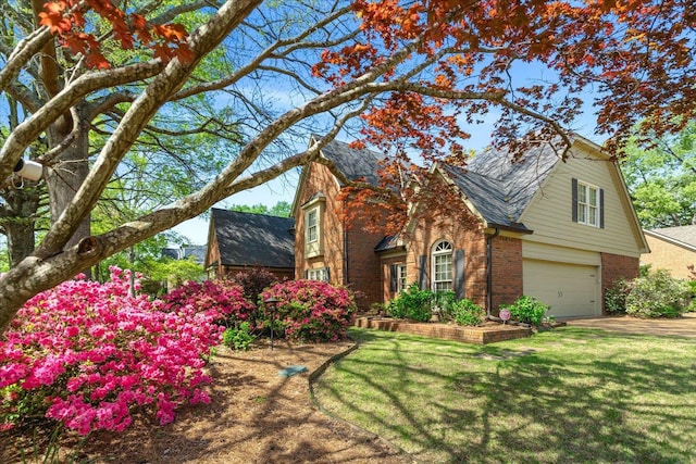 traditional-style house with concrete driveway, brick siding, a front yard, and a garage