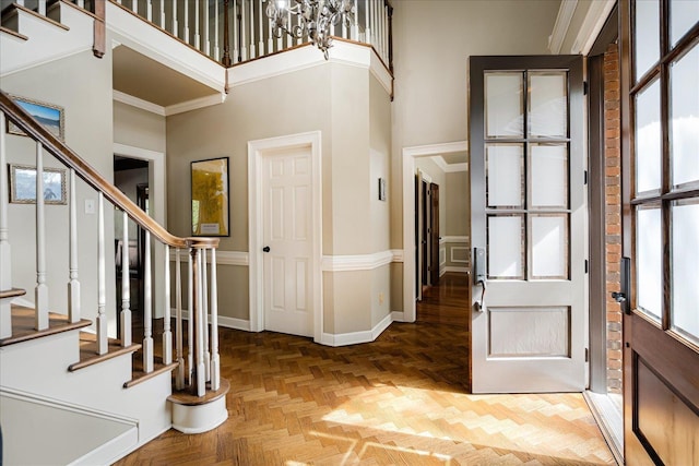 entryway with stairway, a high ceiling, baseboards, and ornamental molding