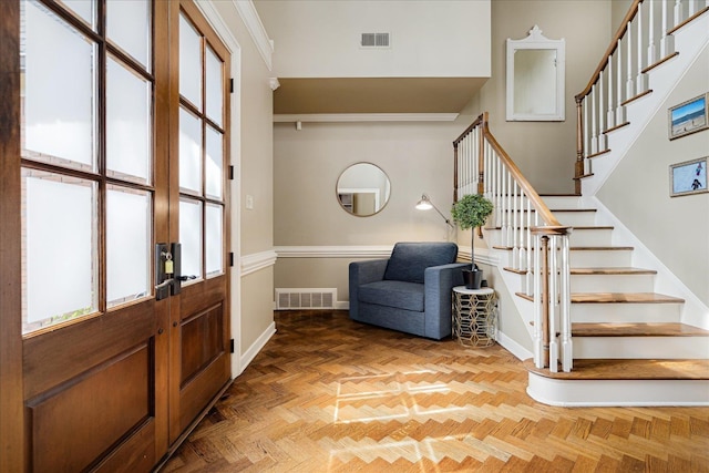 foyer entrance with baseboards, a towering ceiling, stairs, and visible vents