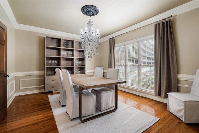 dining area featuring wood finished floors, crown molding, and a notable chandelier