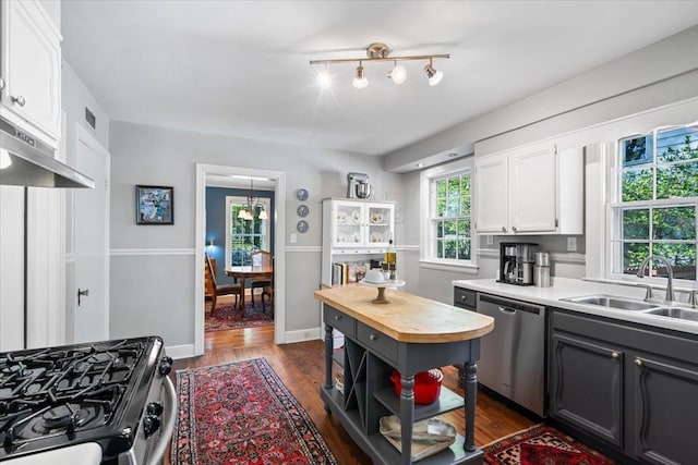 kitchen with stainless steel dishwasher, a sink, white cabinets, dark wood-style flooring, and gas stove