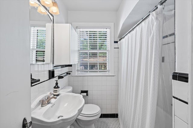 full bathroom with tile walls, plenty of natural light, a sink, and toilet