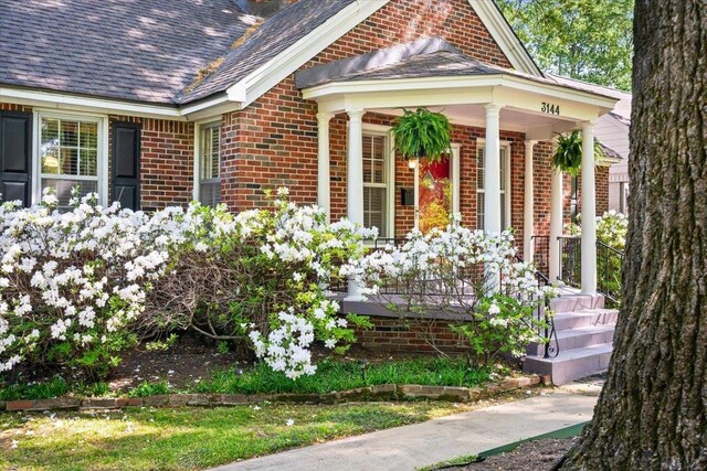 view of home's exterior with brick siding and covered porch