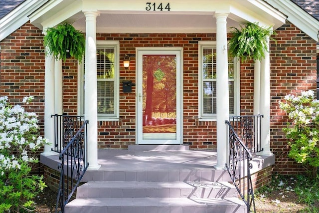 entrance to property with brick siding and covered porch