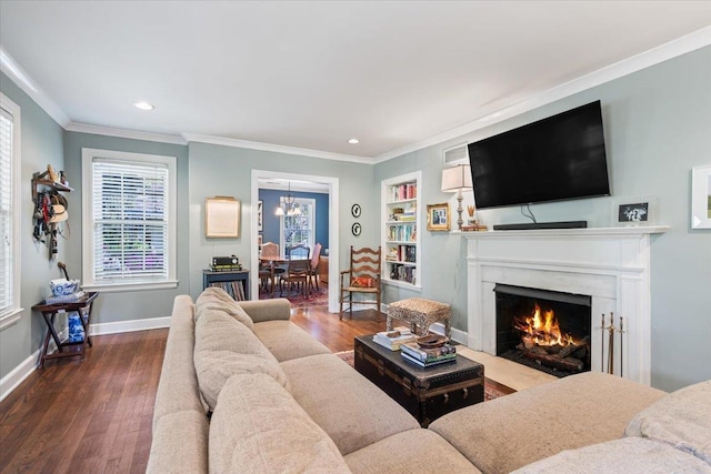 living area with a premium fireplace, wood finished floors, ornamental molding, and an inviting chandelier