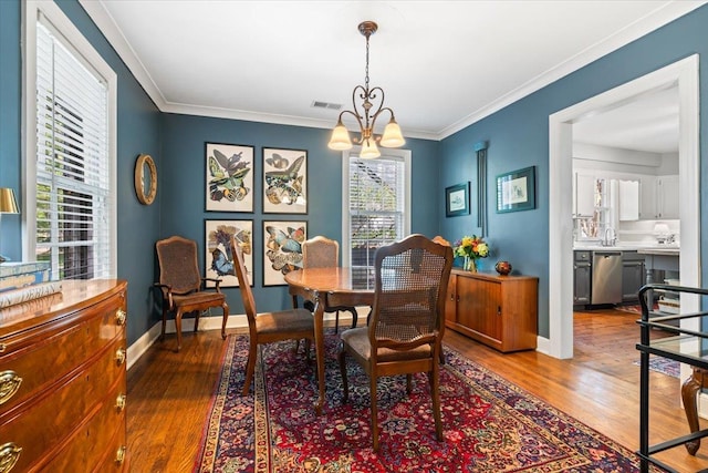 dining area with baseboards, a notable chandelier, wood finished floors, and visible vents
