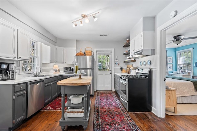 kitchen featuring a sink, butcher block countertops, gray cabinetry, open shelves, and appliances with stainless steel finishes