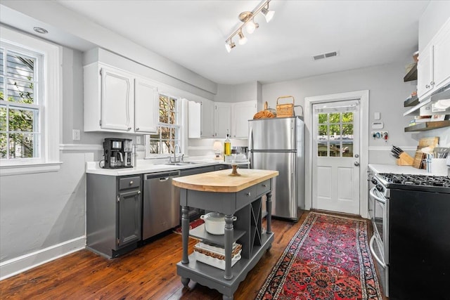 kitchen with open shelves, a sink, wooden counters, dark wood finished floors, and appliances with stainless steel finishes