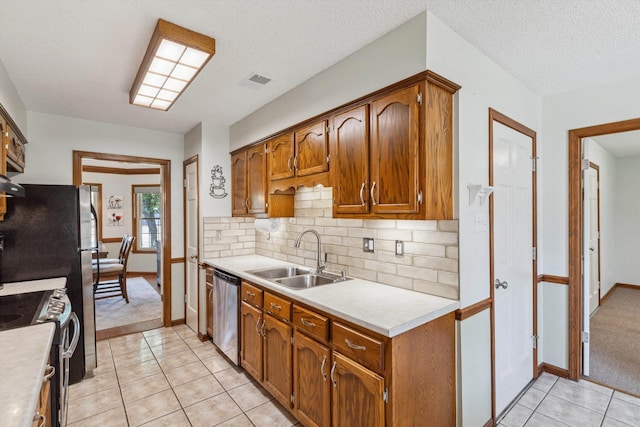 kitchen with light countertops, light tile patterned flooring, stainless steel appliances, and a sink